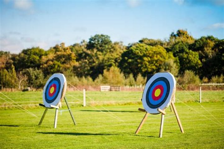 Points an arrow toward a target at the archery range